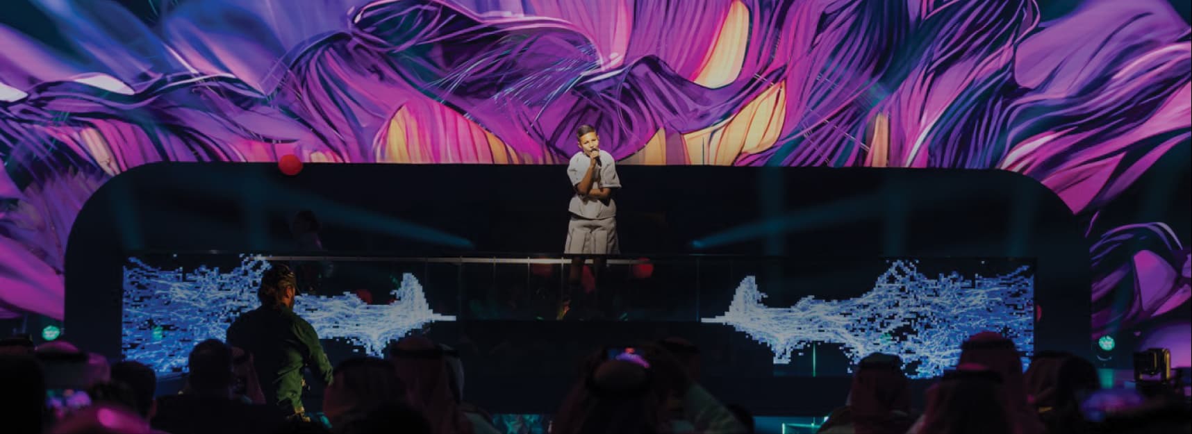 Performance on stage with audience silhouettes and colorful lighting